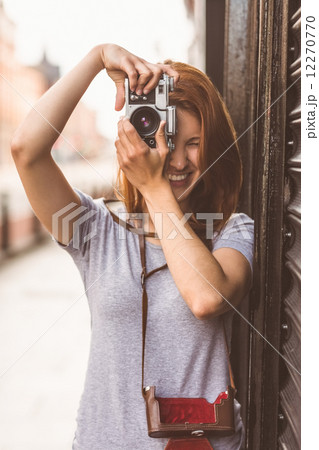 Pretty redhead taking a picture with retro camera 12270770
