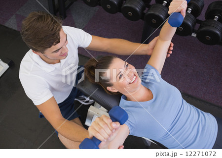 Personal trainer helping client lift dumbbells Personal trainer helping client lift dumbbells 12271072