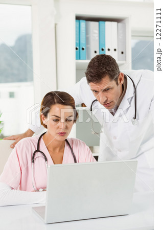 Doctors using laptop together at medical office Doctors using laptop together at medical office 12271111