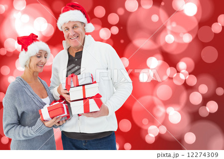 Composite image of festive mature couple holding christmas gifts 12274309