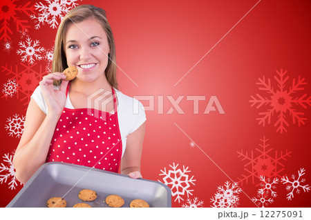 Composite image of pretty homemaker showing hot cookies 12275091