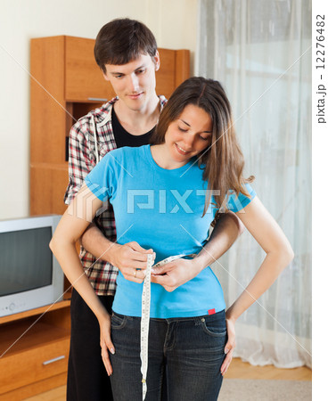 Guy measuring waist of girlfriend Guy measuring waist of girlfriend 12276482