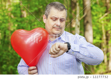 Man with red balloon staring at the clock  12277732