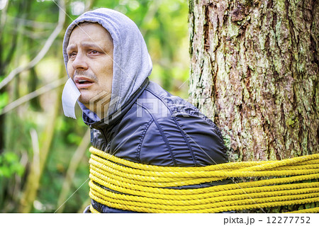Man tied to a tree in the forest 12277752