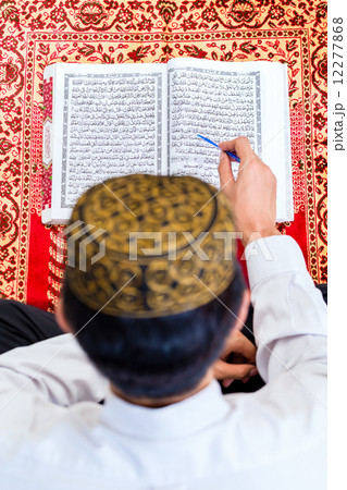 Asian Muslim man studying Koran or Quran 12277868
