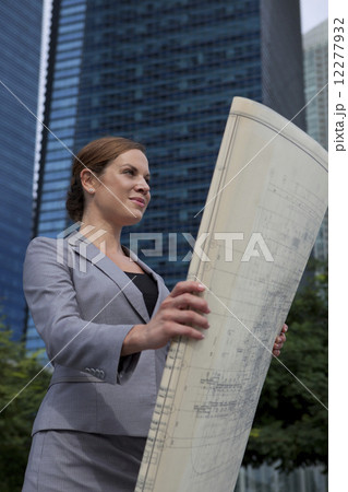Businesswoman looking at architectural plans outdoors Businesswoman looking at architectural plans outdoors 12277932