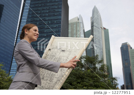 Businesswoman looking at architectural plans outdoors Businesswoman looking at architectural plans outdoors 12277951