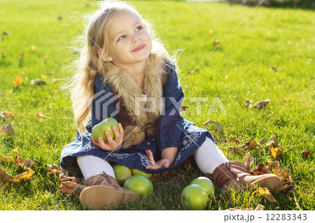 Child with green apples sitting on grass 12283343