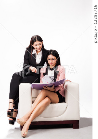 Two female executive in friendly discussion over a sofa Two female executive in friendly discussion over a sofa 12283716