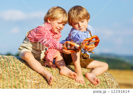 Two little sibling boys and friends sitting on hay stack  and ea 12291614