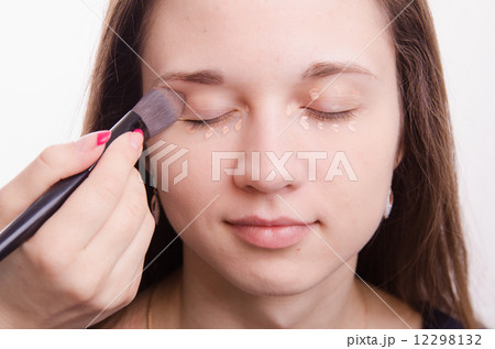 Makeup artist is shaded brush concealer on eyelids model Makeup artist is shaded brush concealer on eyelids model 12298132