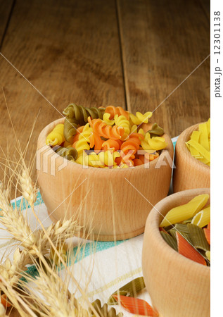 Raw tricolor pasta set on the wooden table Raw tricolor pasta set on the wooden table 12301138