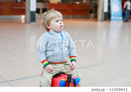 Funny toddler boy going on vacations trip with suitcase at airpo Funny toddler boy going on vacations trip with suitcase at airpo 12309642