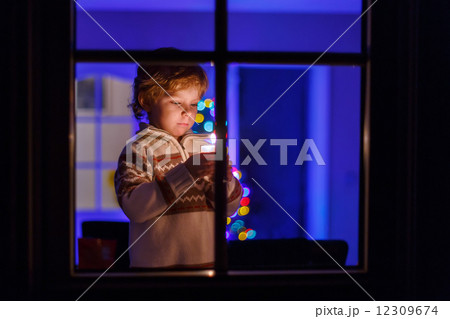 Sweet child standing by window at Christmas time and holding can 12309674