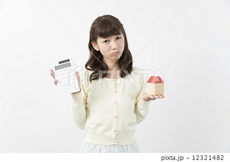 電卓と家を持って悩む若い女性 マイホーム検討 電卓と家を持って悩む若い女性 マイホーム検討 12321482