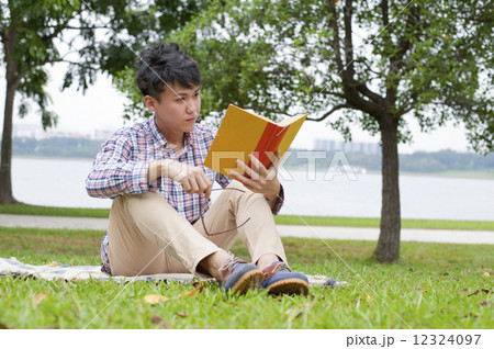 Young guy reading in a park. Young guy reading in a park. 12324097