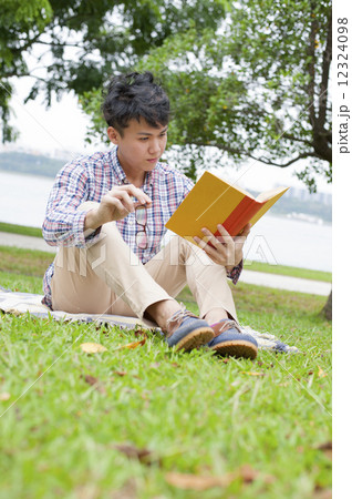Young guy reading in a park. Young guy reading in a park. 12324098