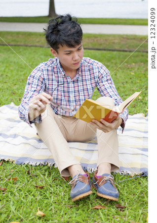 Young guy reading in a park. 12324099