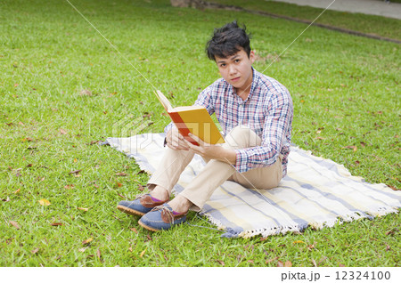 Young guy reading in a park. Young guy reading in a park. 12324100