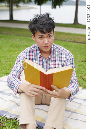 Young guy reading in a park. 12324101