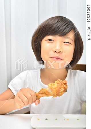 フライドチキンを美味しそうに食べる女の子の写真素材