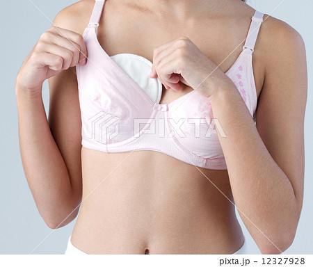 Woman putting absorbent pad to her breast for protect milk dripping Woman putting absorbent pad to her breast for protect milk dripping 12327928