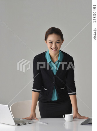 an asian office lady standing in front of her desk 12330491