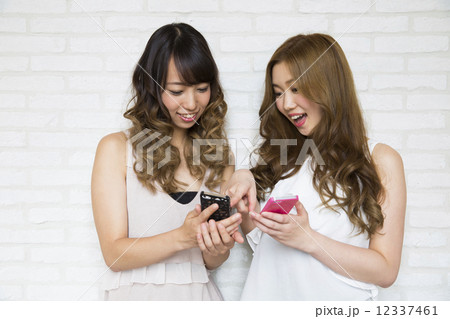 スマホを操作する若い女性2人 12337461