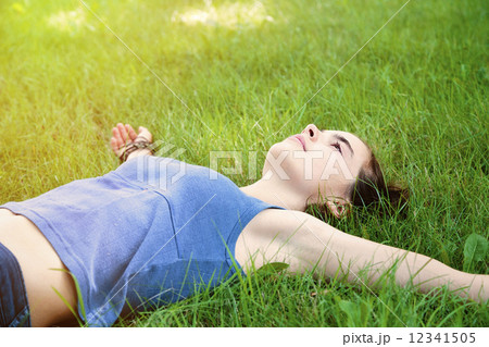 teenage girl laying on a meadow with stretched out arms 12341505