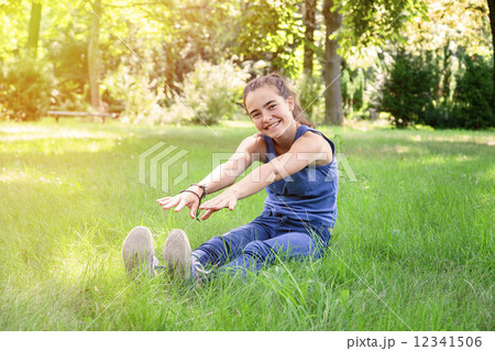 smiling teenage girl trying to touch the feet with their hands 12341506