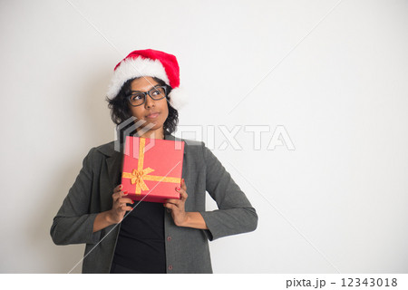 Young African American woman wearing a santa hat opening a gift Young African American woman wearing a santa hat opening a gift 12343018