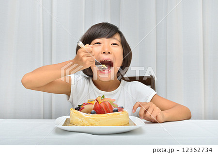デコレーションケーキを美味しそうに食べる女の子の写真素材