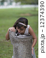 Young Indian Girl drinking from water cooler in park 12374390