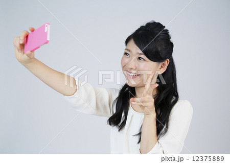 スマホで自撮りをする若い女性の写真素材