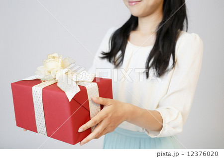 プレゼントを渡す若い女性 12376020