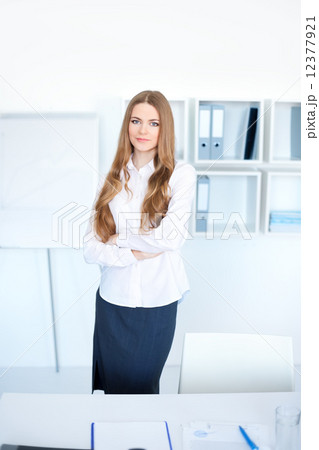 Portrait of happy young business woman standing with hands folde 12377921