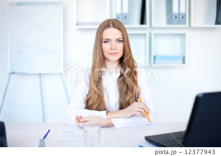 Portrait of beautiful young business woman sitting at desk in br Portrait of beautiful young business woman sitting at desk in br 12377943