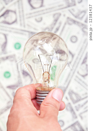 hand holding eco light bulb on dollars background 12381437