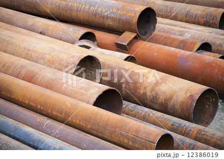 Pile of rusted industrial steel pipes lay on the ground 12386019