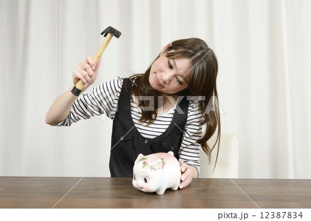 貯金箱を壊す若い女性 12387834