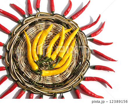 Red and yellow chili peppers on a wicker stand 12389156