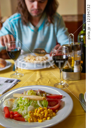 guy blue shirt with long hair eats salad in restaurant 12394732