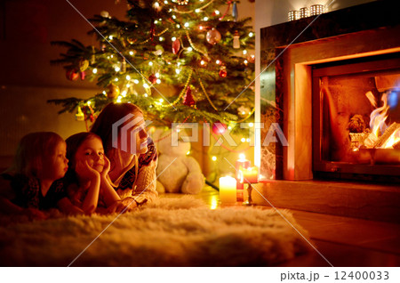 Happy family by a fireplace on Christmas 12400033