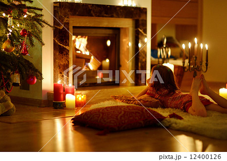 Happy little girl by a fireplace on Christmas 12400126