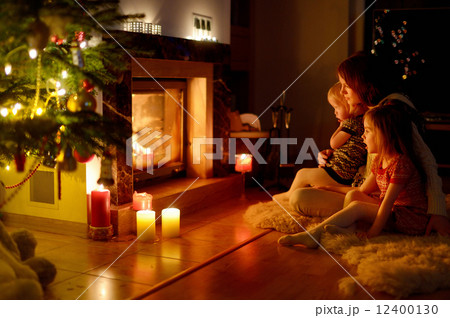 Happy family by a fireplace on Christmas 12400130