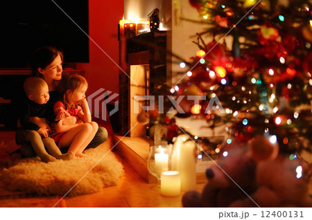 Young mother and her daughters by a fireplace 12400131