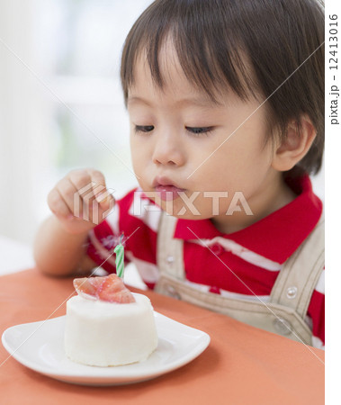 ケーキのろうそくに息を吹く男の子 12413016