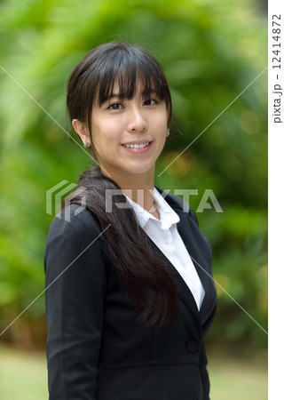 Portrait of one successful chinese business woman in suit in front of greenery 12414872