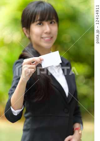 One successful young chinese business woman showing her business name card in front of greenery One successful young chinese business woman showing her business name card in front of greenery 12414911