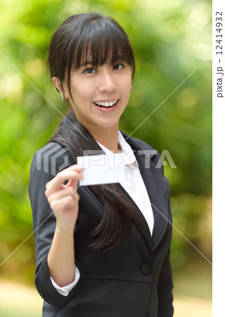 One successful young chinese business woman showing her business name card in front of greenery 12414932